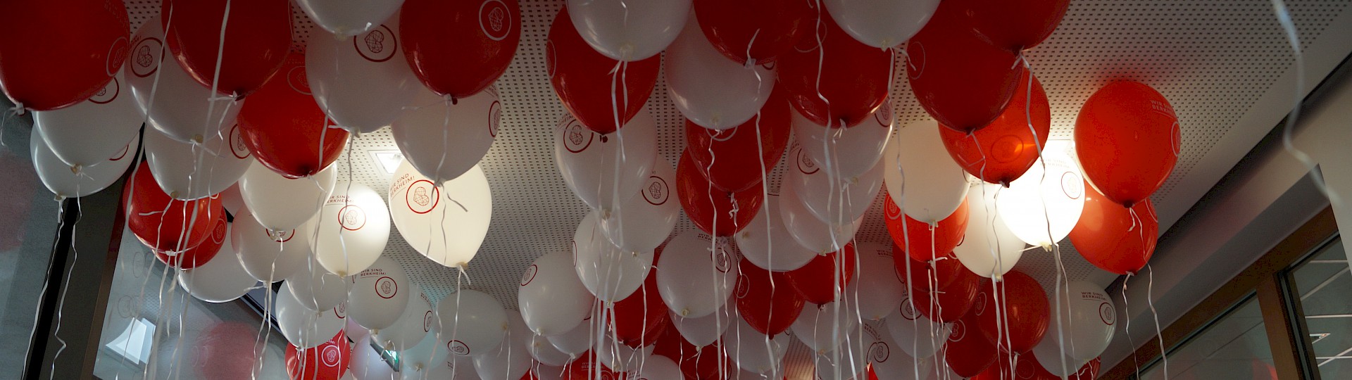 Rote und Weiße Luftballons mit dem Wir sind Berkheim Logo die im Rathaus an der Decke schweben