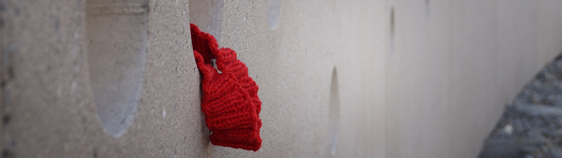 Rotes Häckelband in einer Betonwand (Gemeindekunstprojekt)