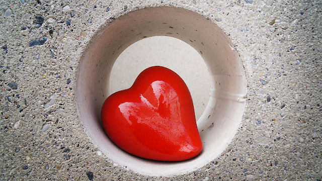 Rotes Herz aus Ton geformt liegt in einer Öffnung in einer Betonwand (Gemeindekunstprojekt)