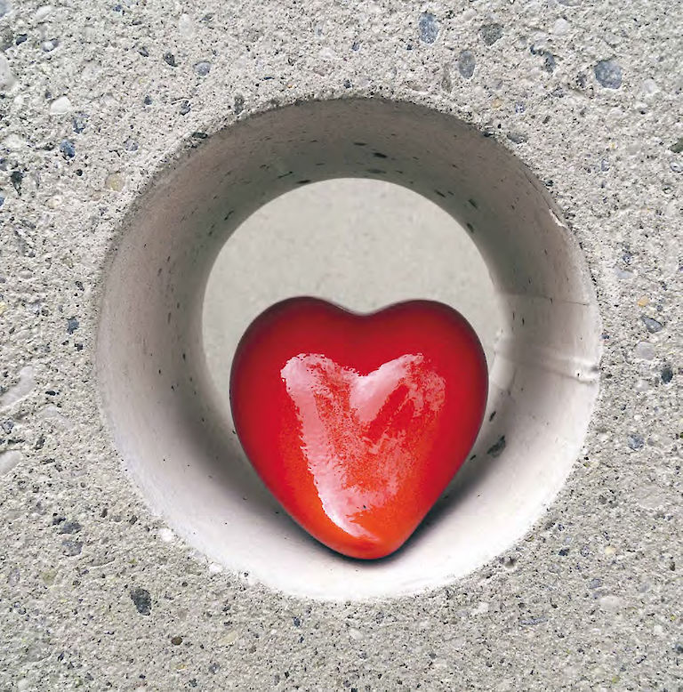 Rotes Herz aus Ton geformt liegt in einer Öffnung in einer Betonwand (Gemeindekunstprojekt)